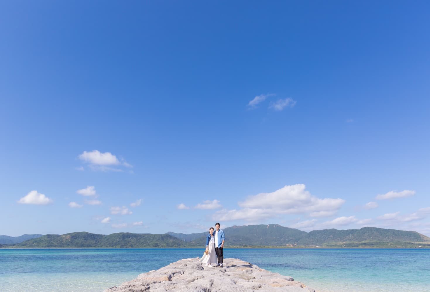 小浜じまの海を背景に立つ新郎新婦