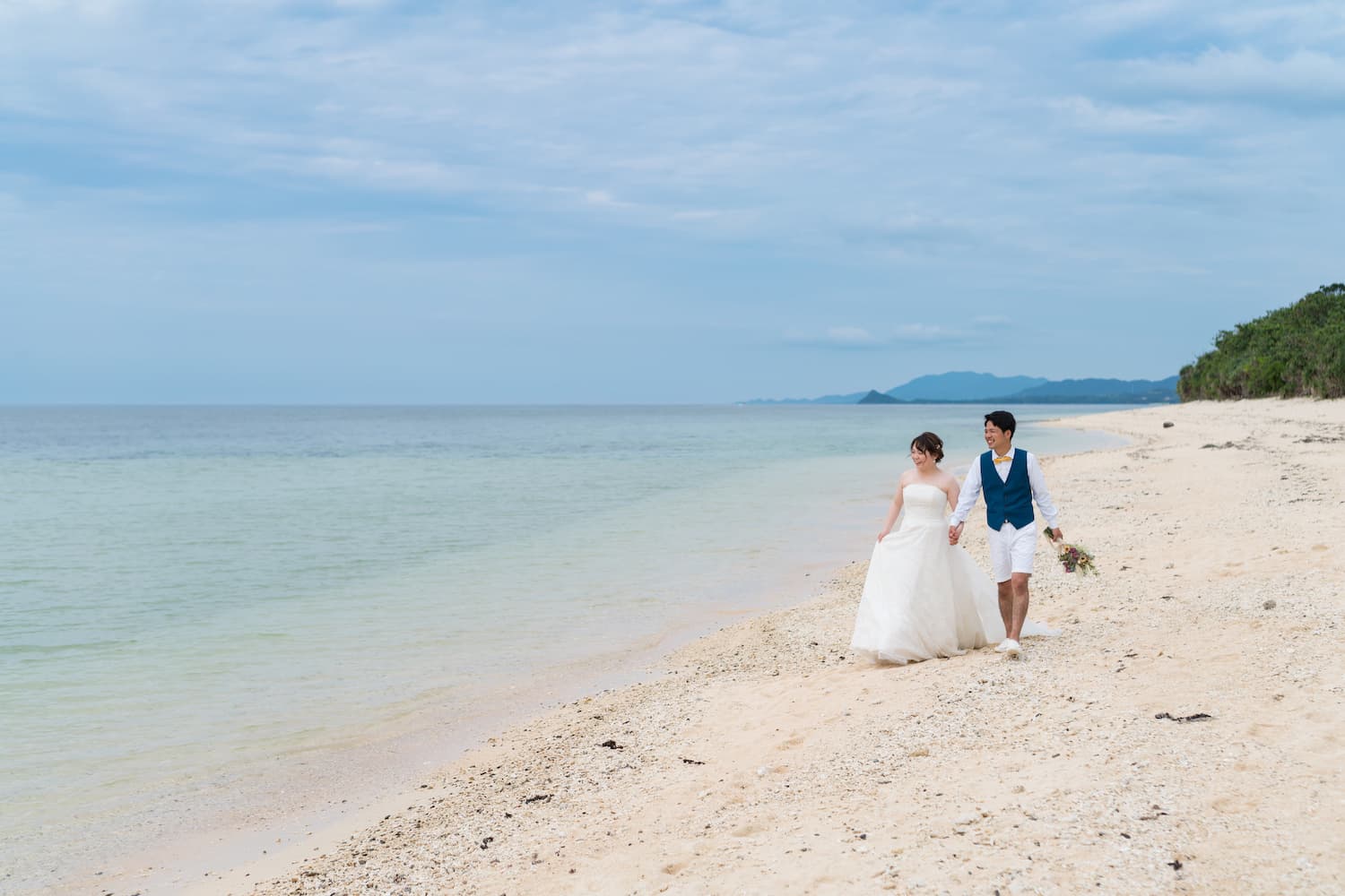 浜辺を歩く新郎新婦