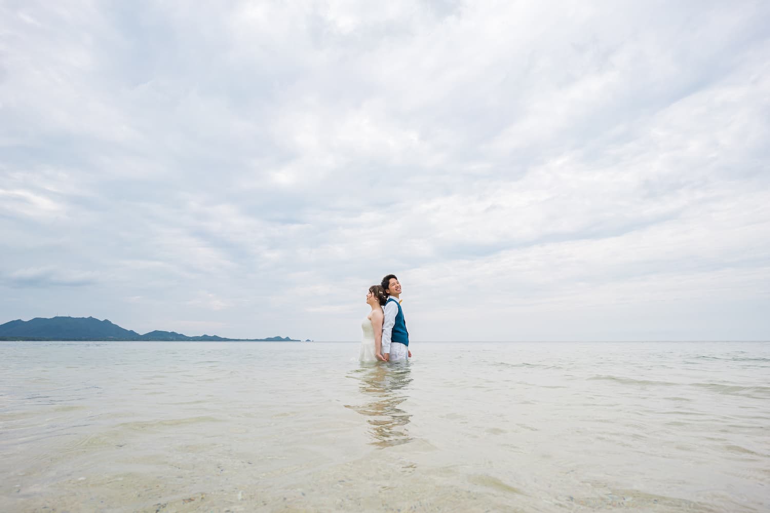 海に入って空を眺める新郎新婦