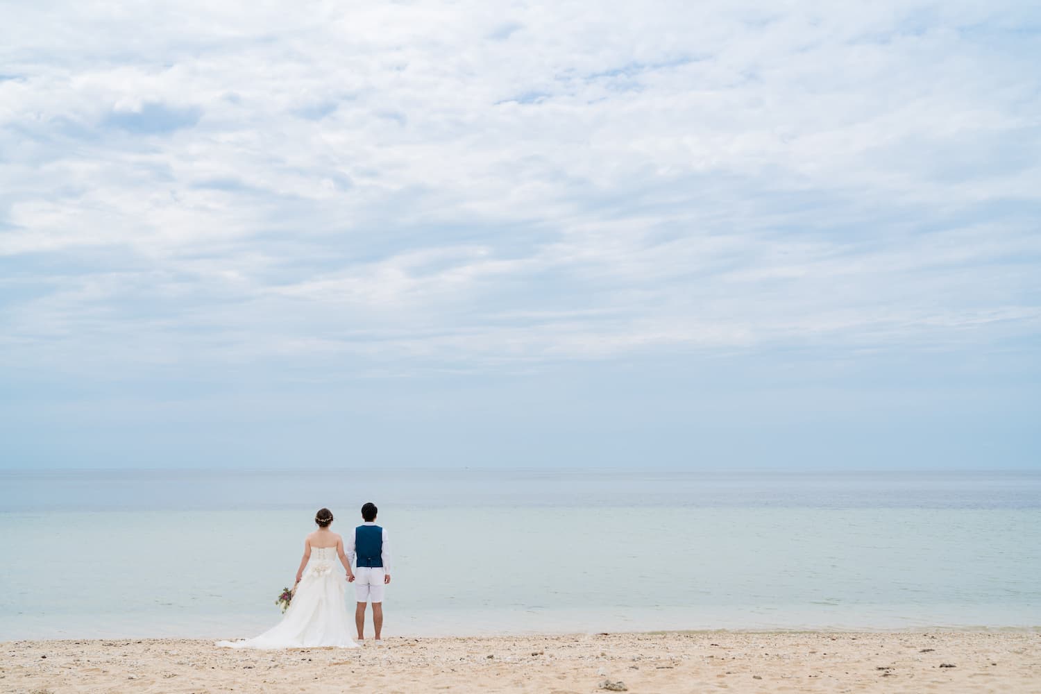 海を眺める新郎新婦の後ろ姿