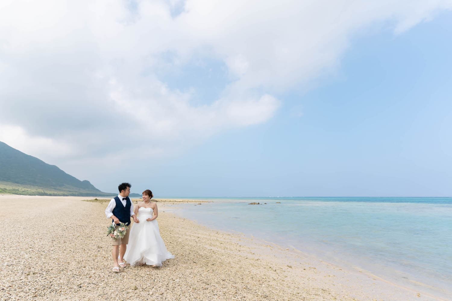 浜辺を歩く新郎新婦