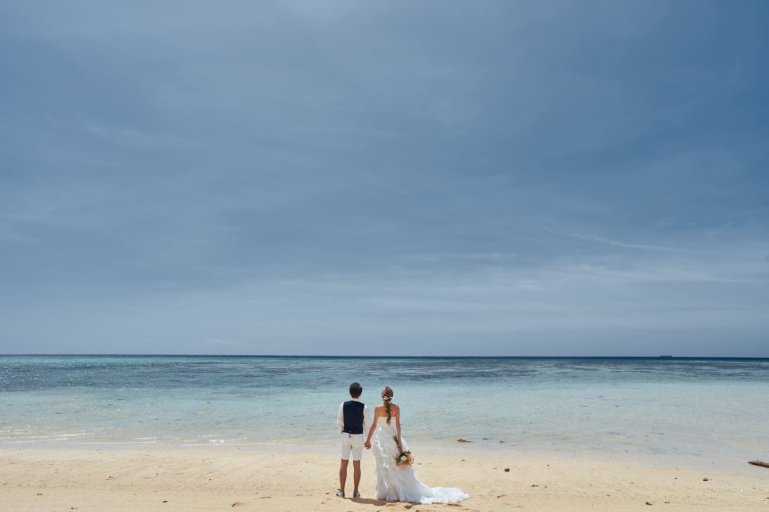 海を眺める新郎新婦の後ろ姿