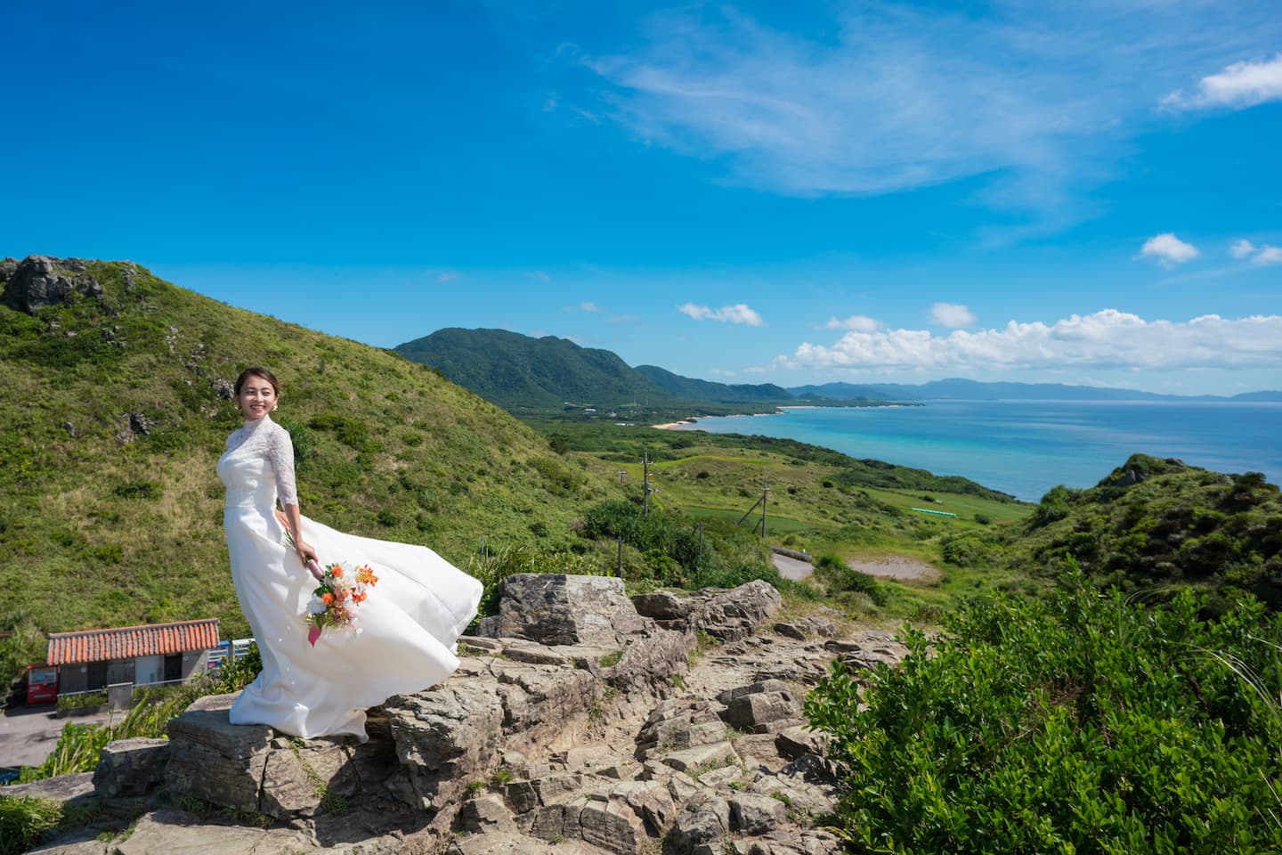 平久保崎灯台にある崖で島の風景を背景に立つ新婦
