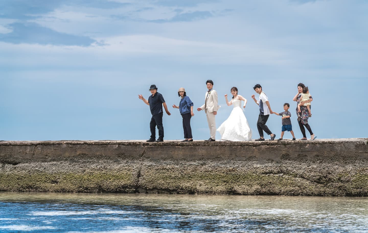 家族と一緒に竹富島の西桟橋を歩く新郎新婦