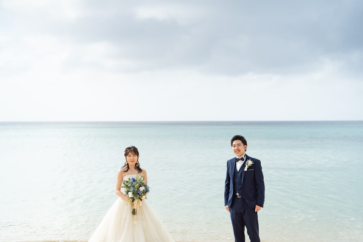石垣島の海を背景に立つ新郎新婦