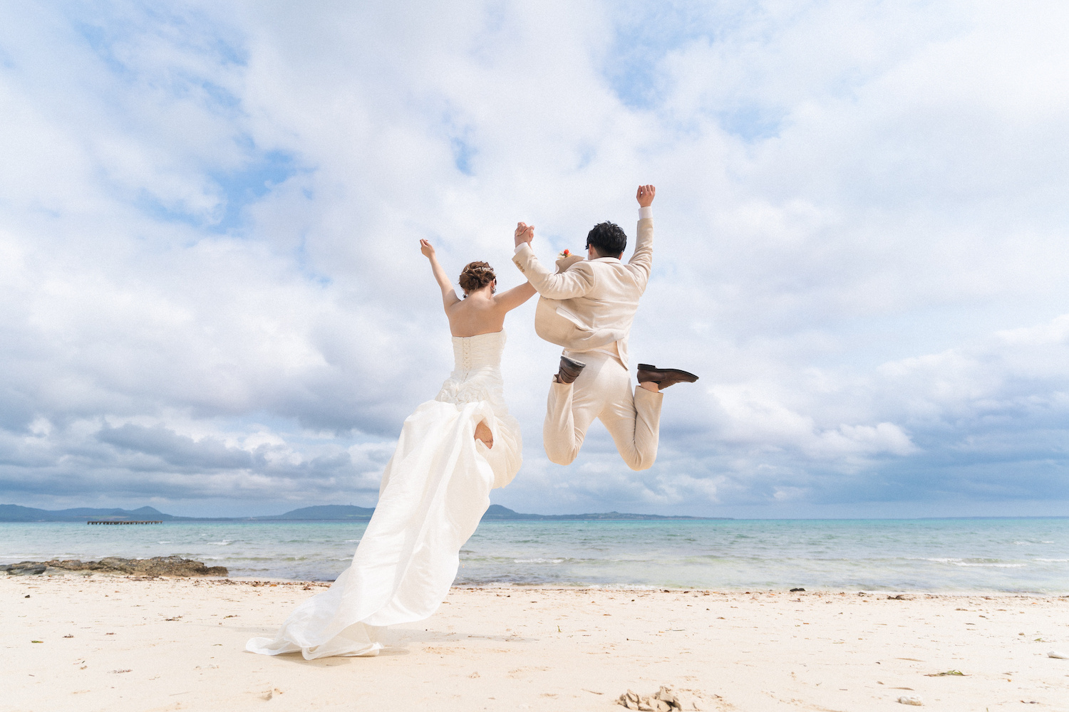 空に向かって大きくジャンプする新郎新婦