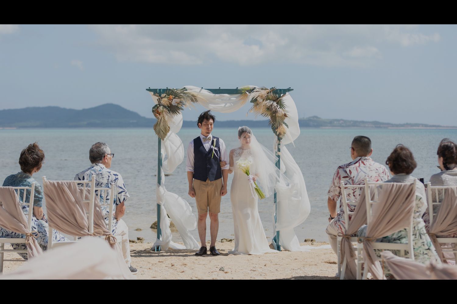 石垣島のビーチで家族に囲まれて挙式を行う新郎新婦