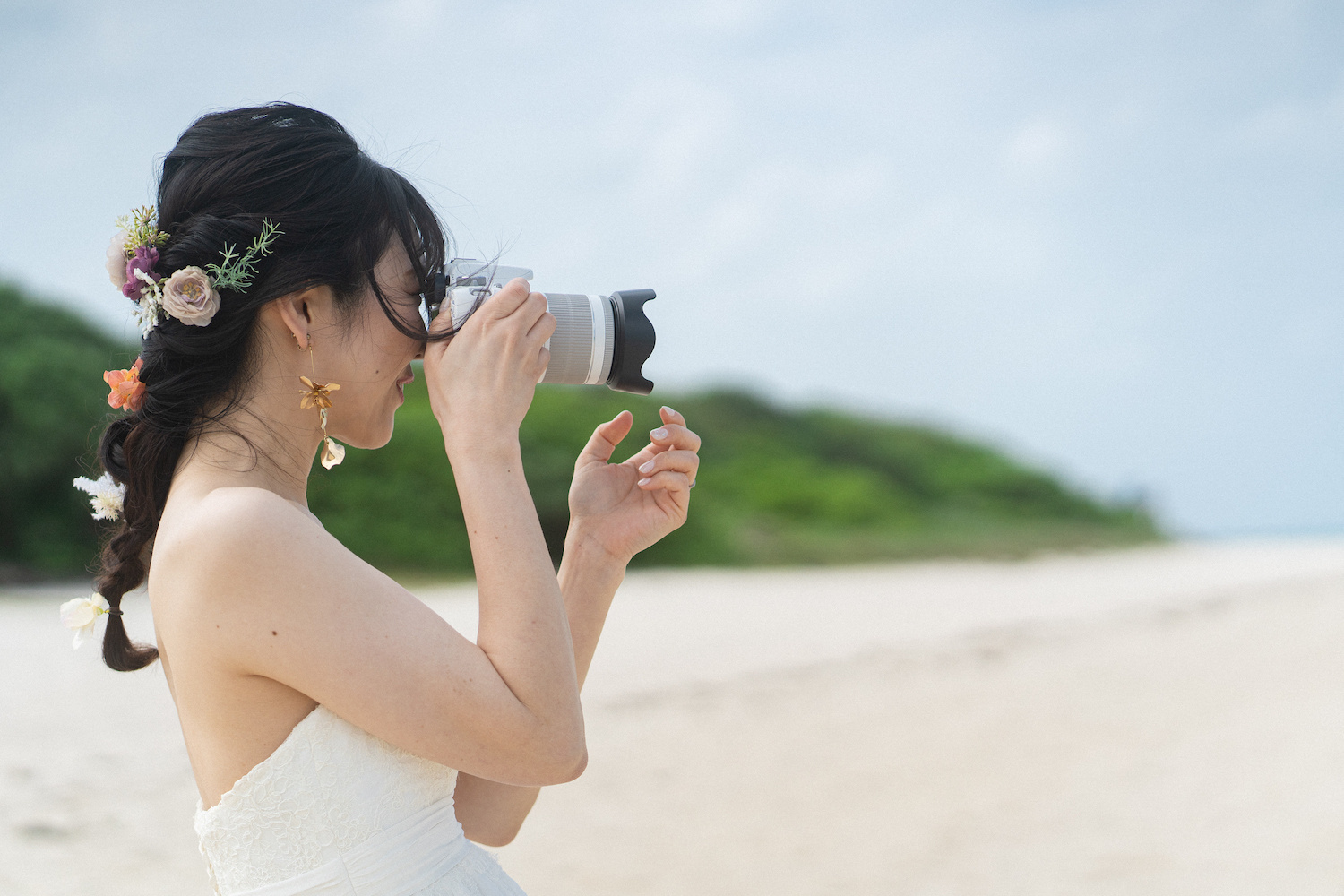  竹富島の海で新郎を撮影する新婦