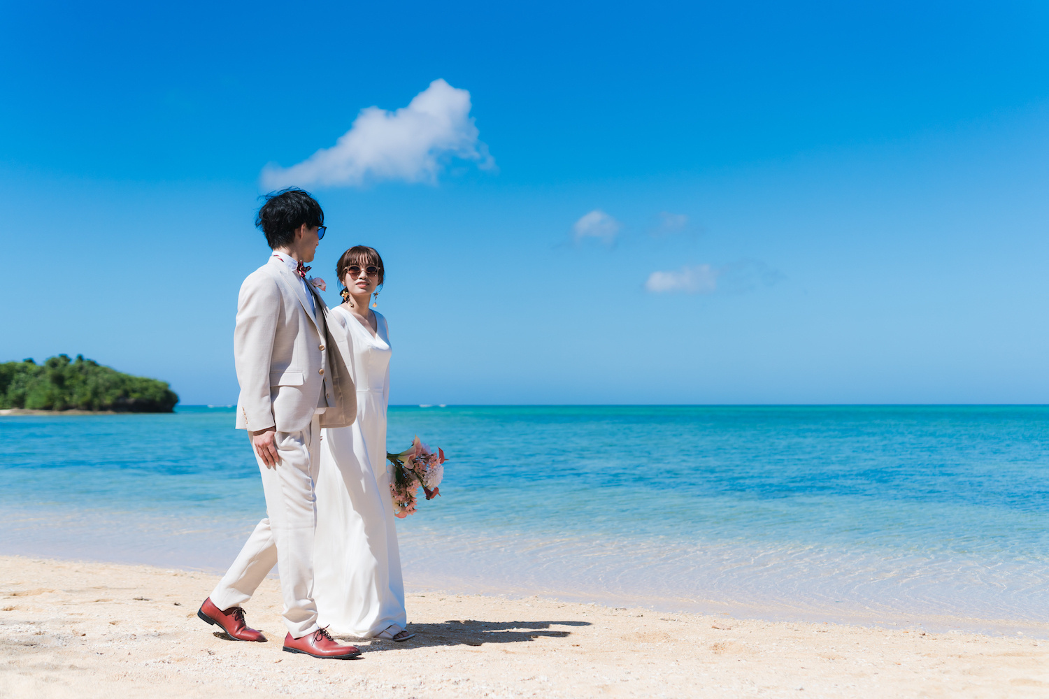 石垣島の青い海を背景に波打ち際を歩く新郎新婦