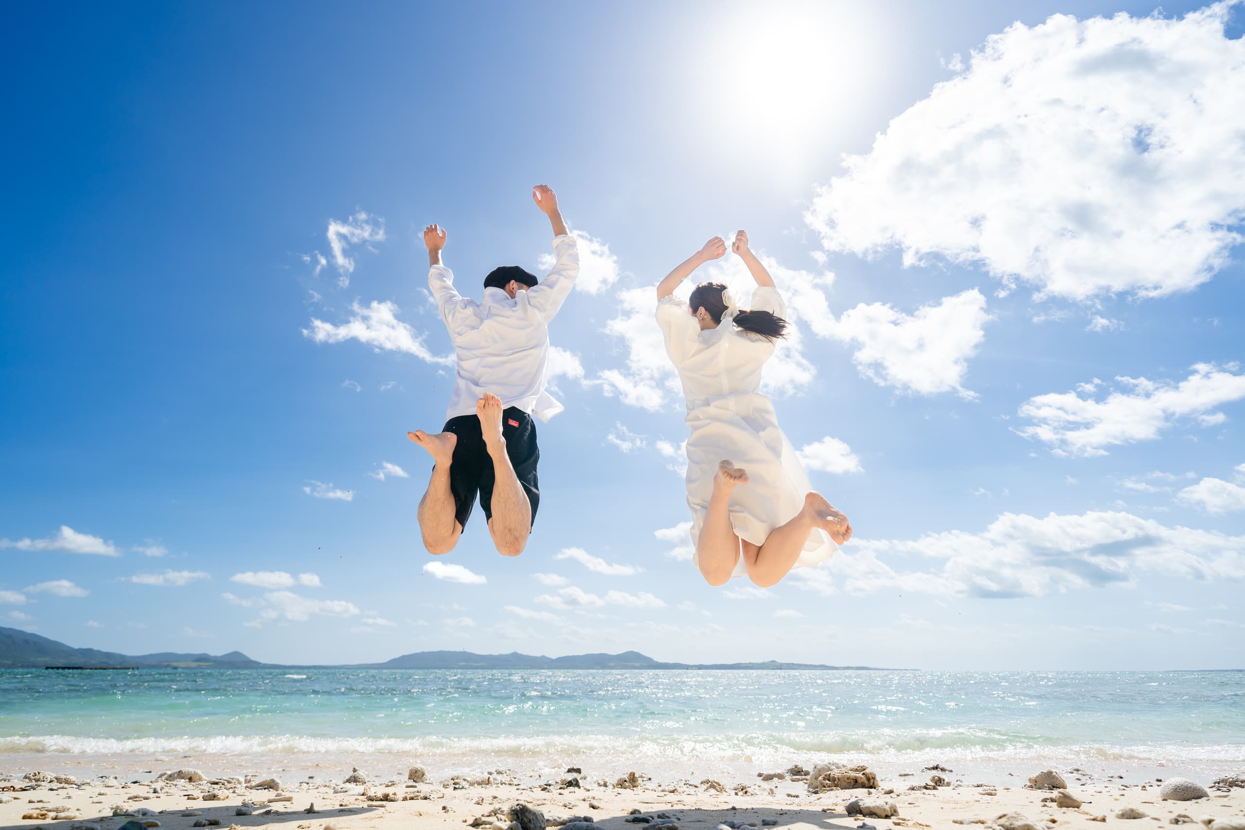 青い空に向かって大きくジャンプする新郎新婦