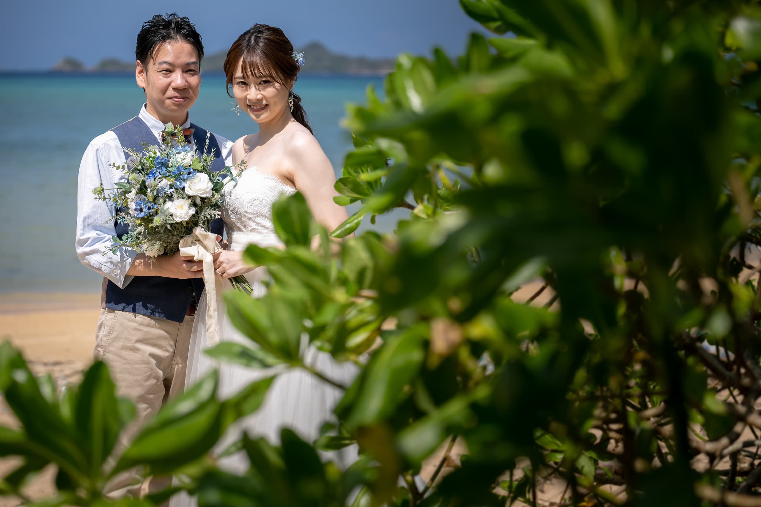 海を背景に二人でブーケを持つ新郎新婦