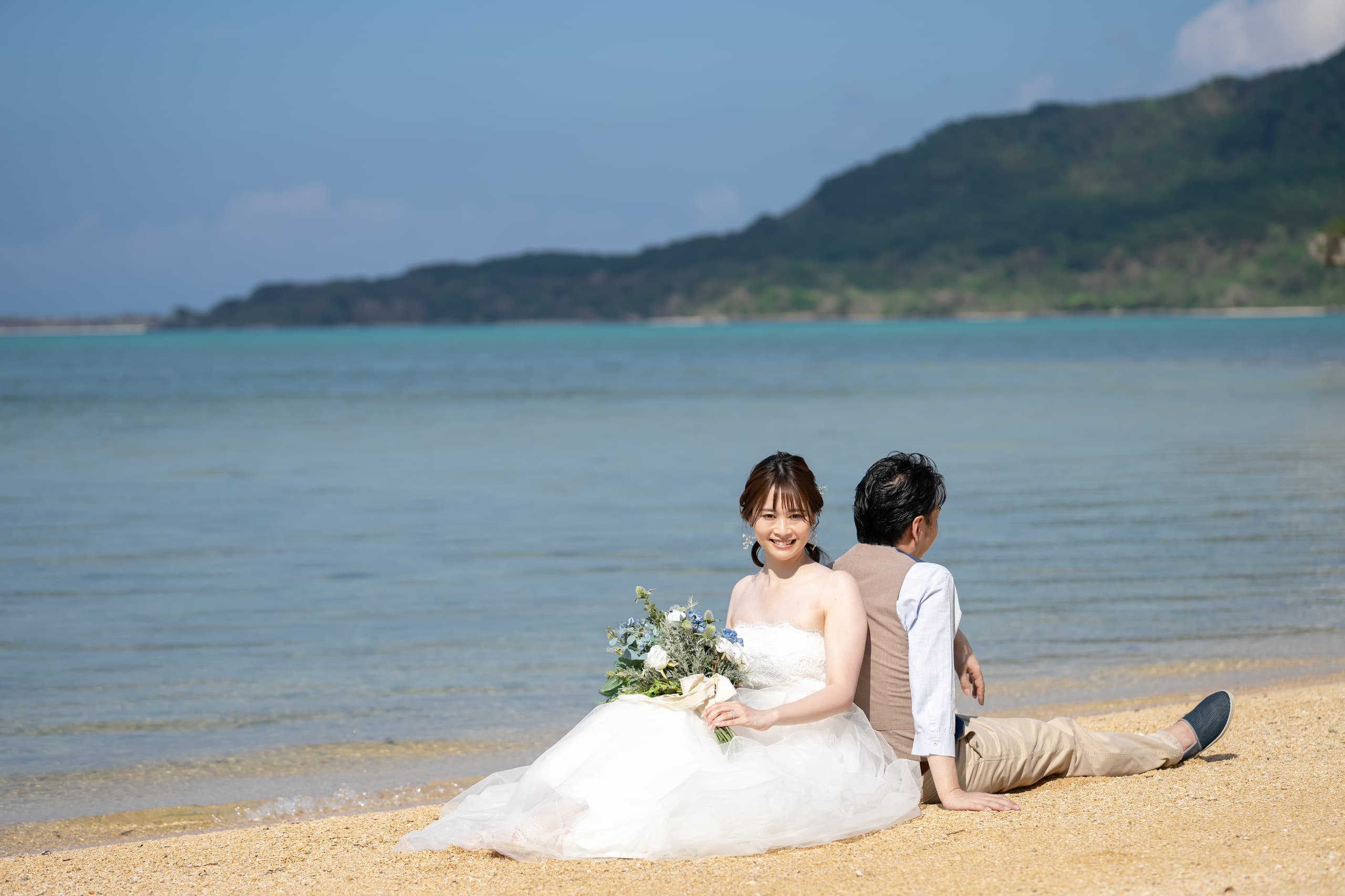 浜辺に座る新郎新婦