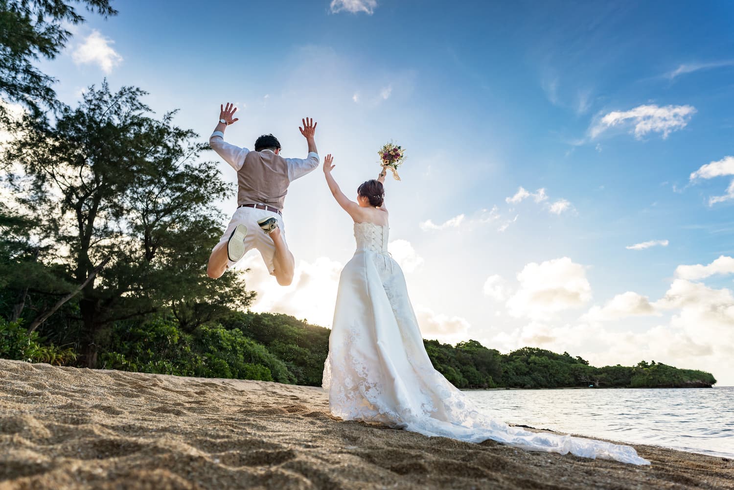 空に向かって大きくジャンプする新郎新婦の後ろ姿