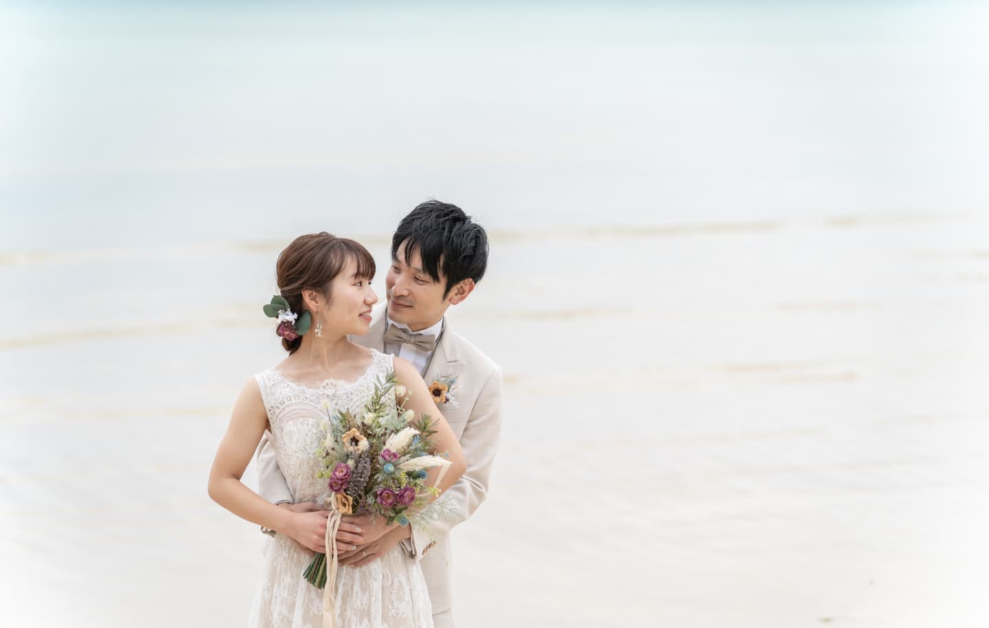 海を背景に抱き合う新郎新婦