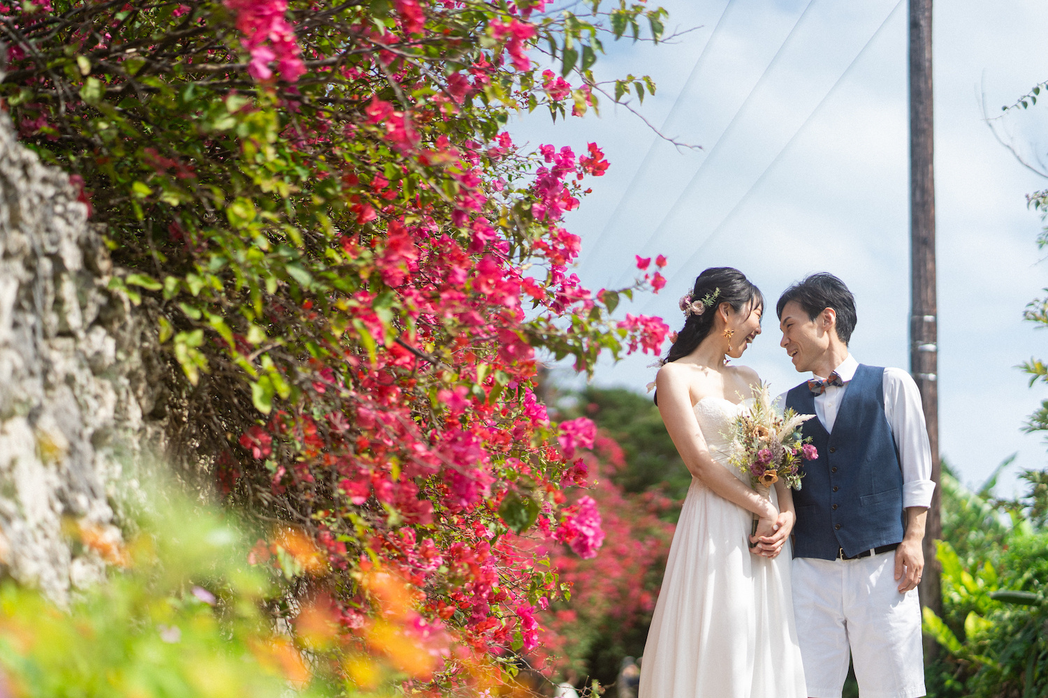 竹富島のブーゲンビリアの前で見つめ合う新郎新婦