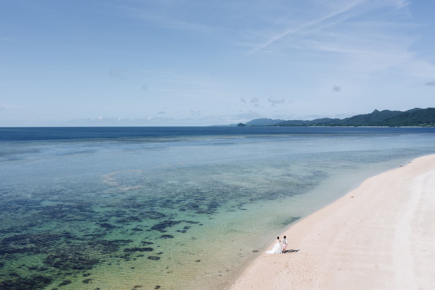 浜辺を歩く新郎新婦のドローン写真