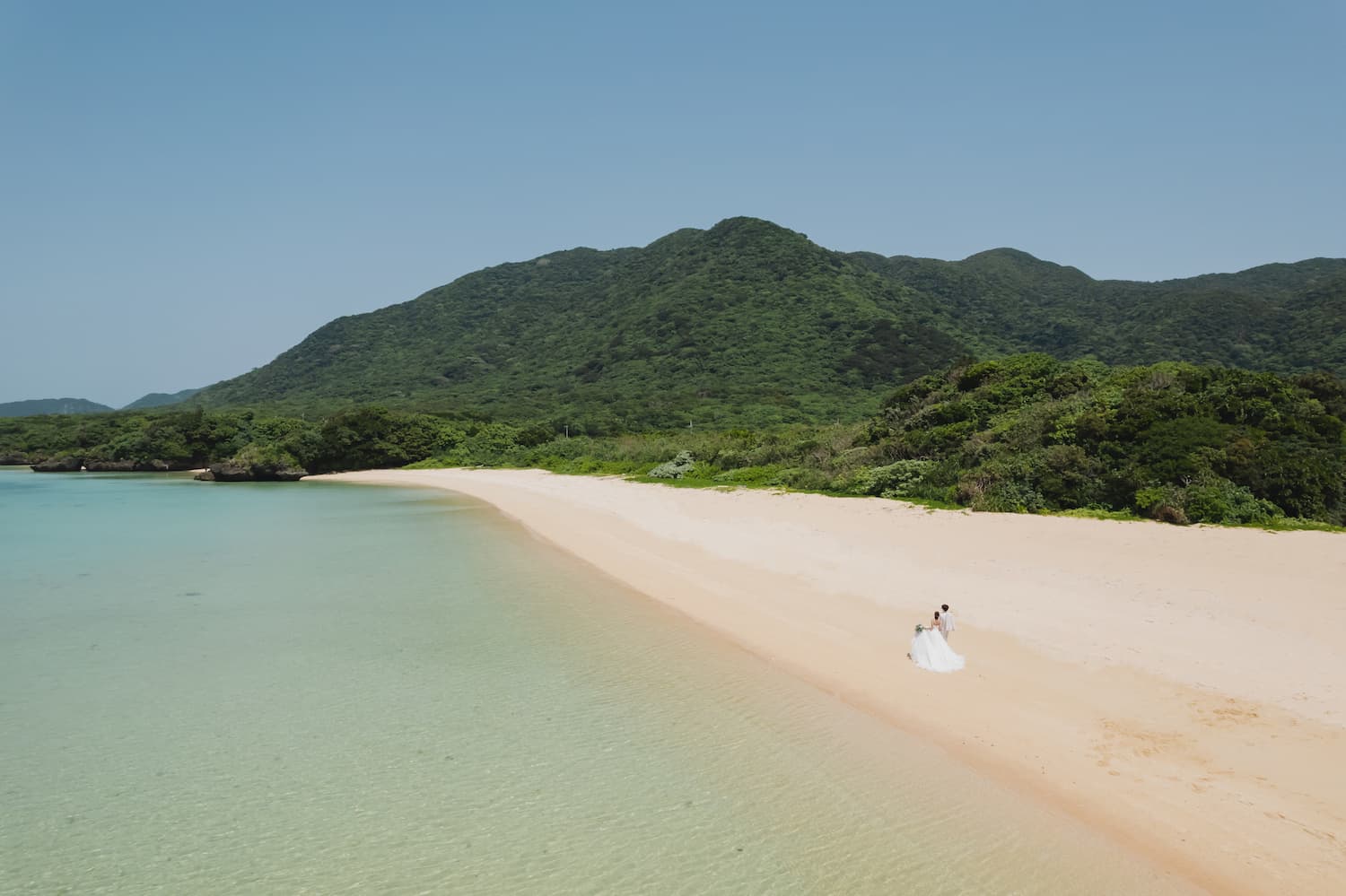 浜辺を歩く新郎新婦を写したドローン写真