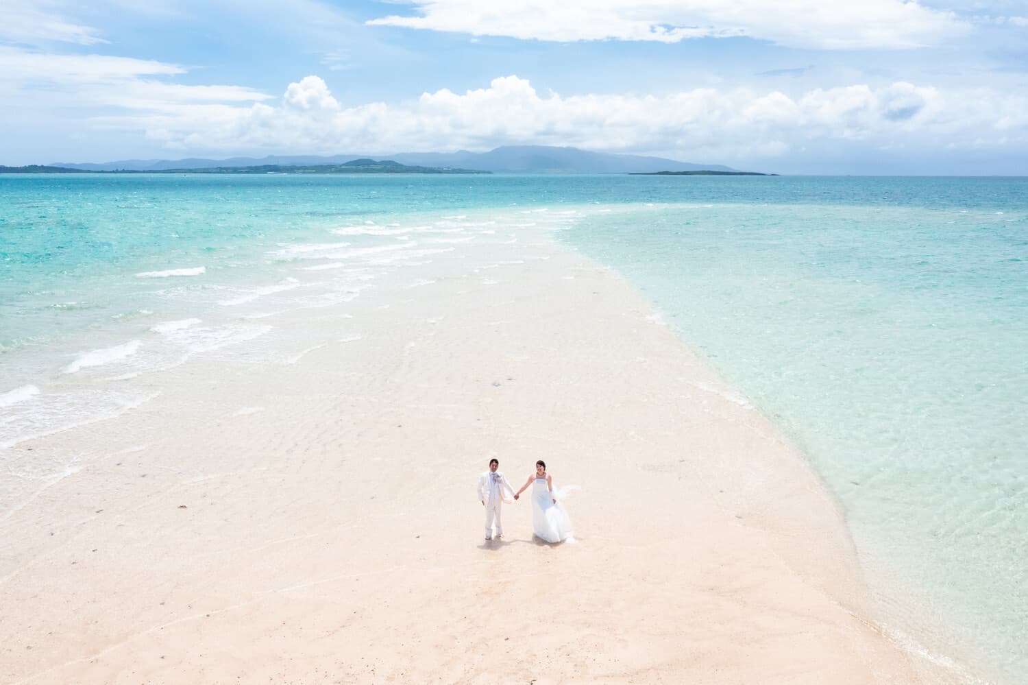 幻の島に立つ新郎新婦を写したドローン写真