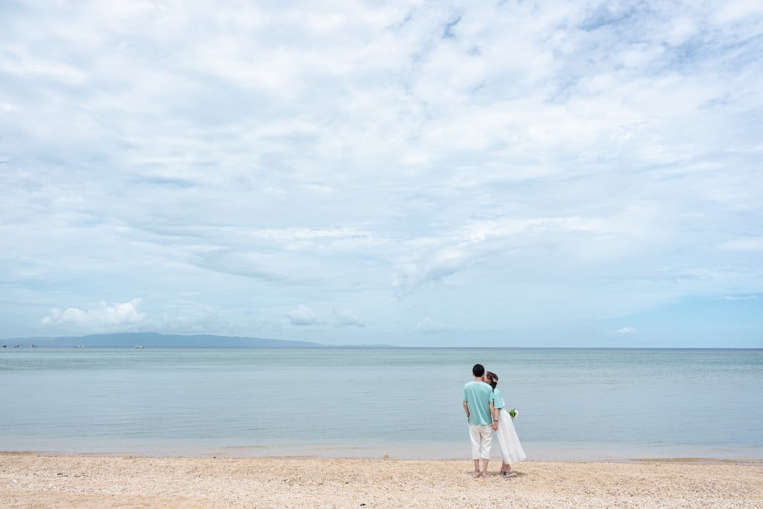 海を眺めながら寄り添う新郎新婦の後ろ姿