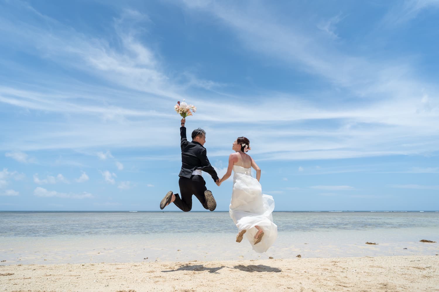 海に向かってジャンプする新郎新婦