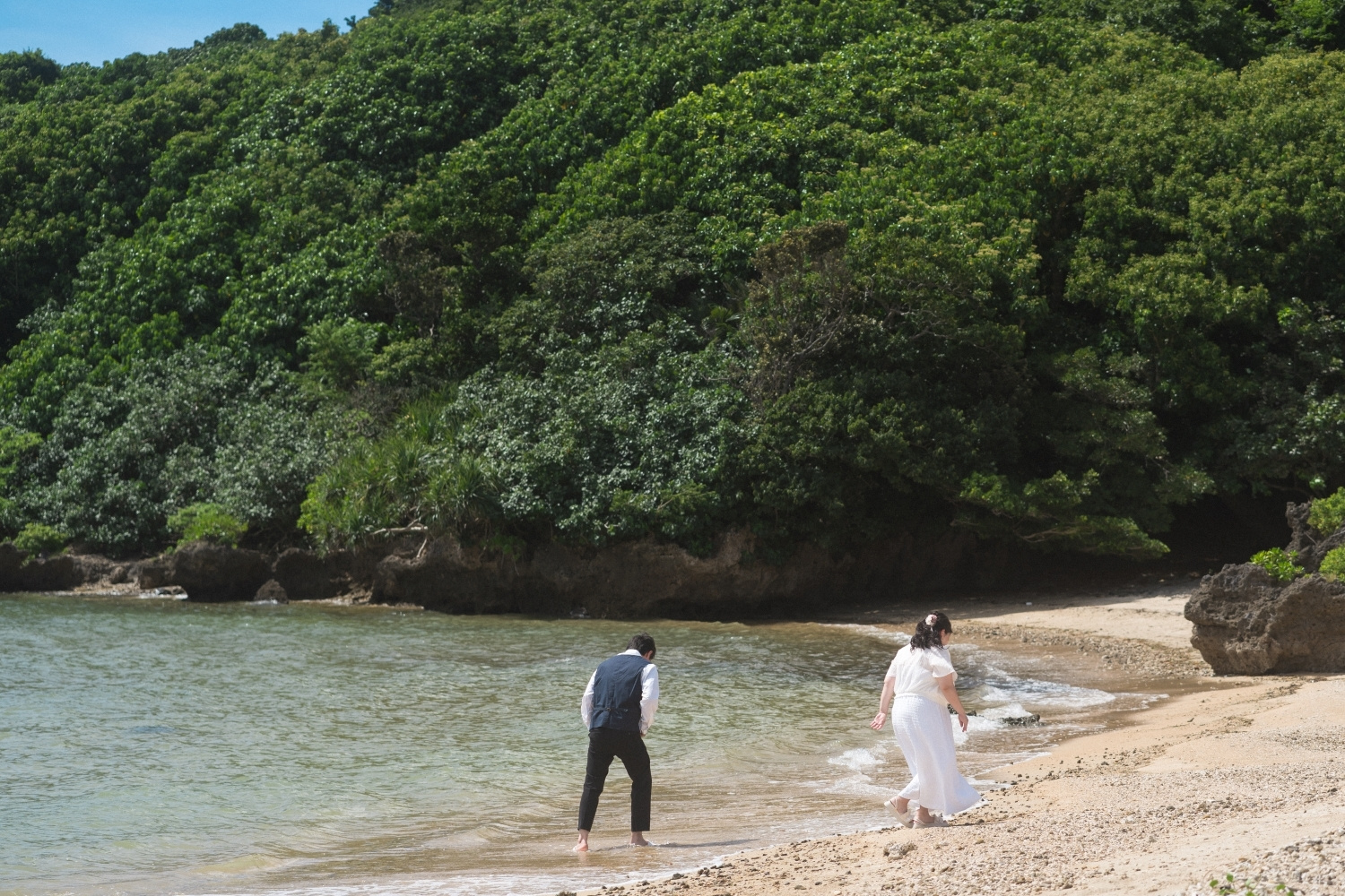 波打ち際を歩く新郎新婦の後ろ姿