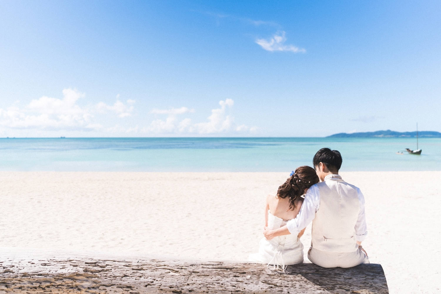 砂浜の流木に腰をかけて竹富島の海を眺める新郎新婦