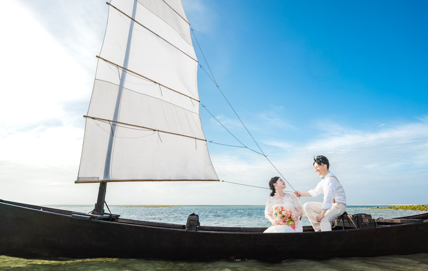 夕焼けが映り込む海を背景に向かい合う新郎新婦