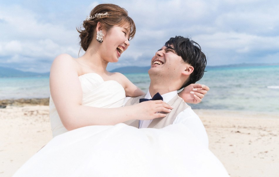 夕焼け空の海で新婦へプロポーズする新郎