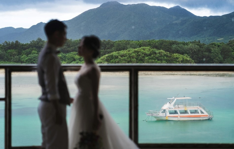 夕焼けに染まる空を背景に新婦へブーケを渡す新郎