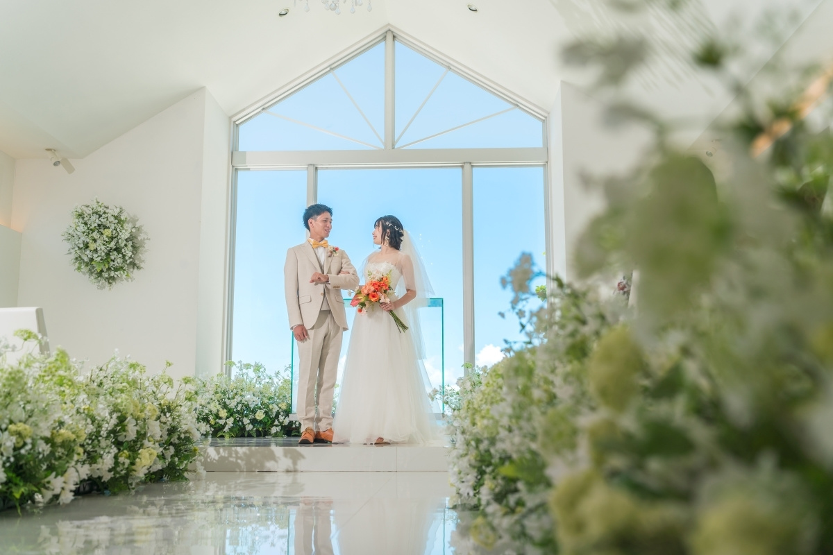 青空が見えるチャペルで見つめ合う新郎新婦