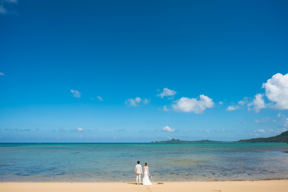 石垣島の海を背景に向かい合って顔を寄せ合う新郎新婦
