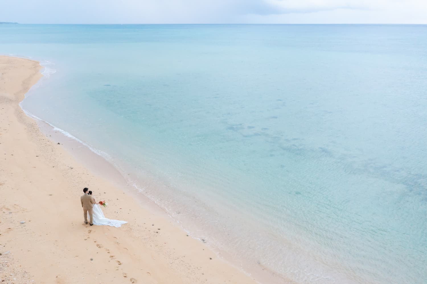 浜辺に立つ新郎新婦のドローン写真