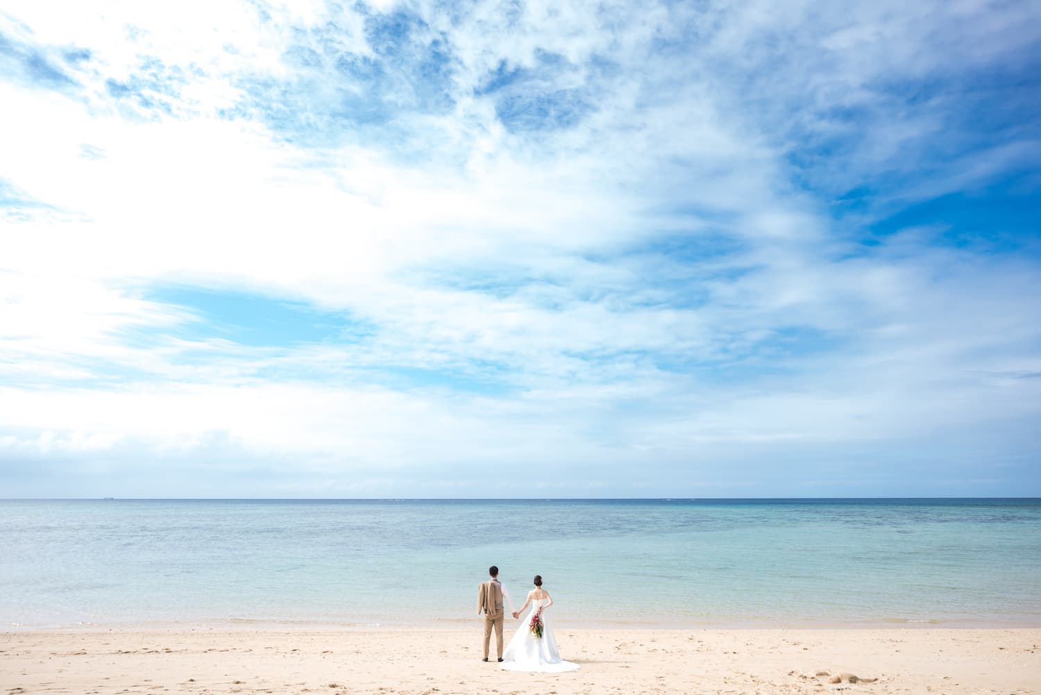 海を眺める新郎新婦の後ろ姿