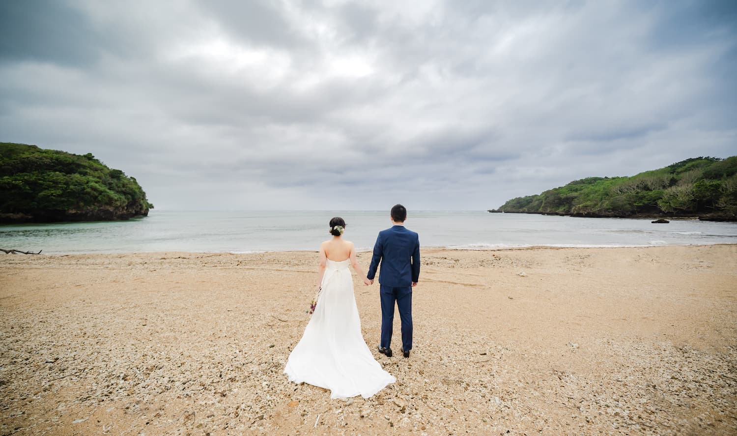 海を眺める新郎新婦の後ろ姿