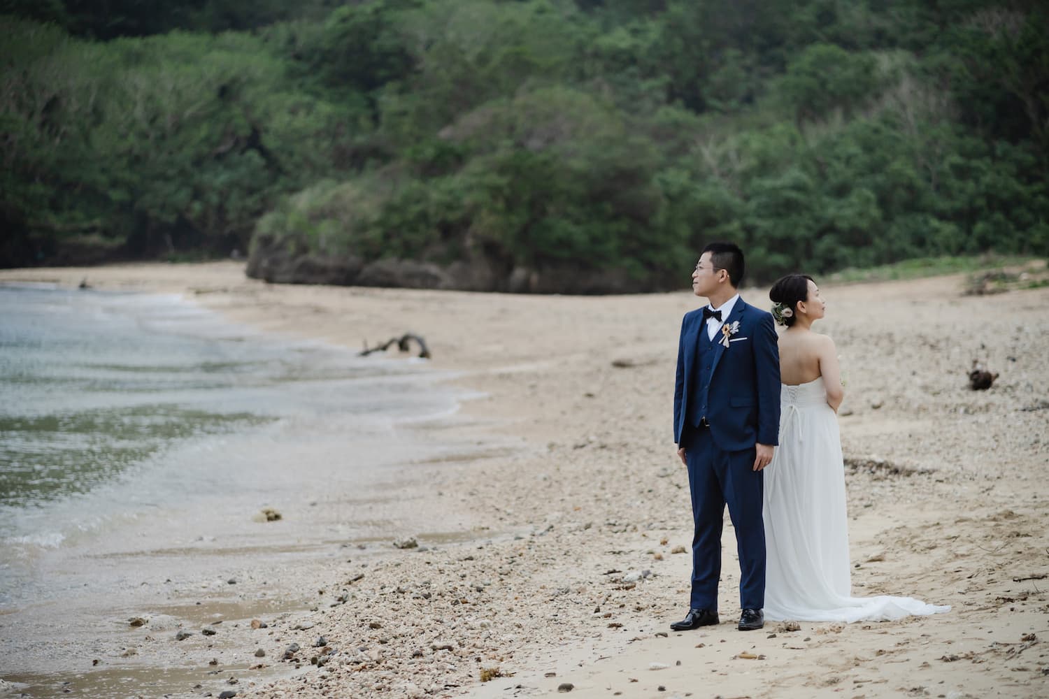 浜辺に背中合わせで立つ新郎新婦