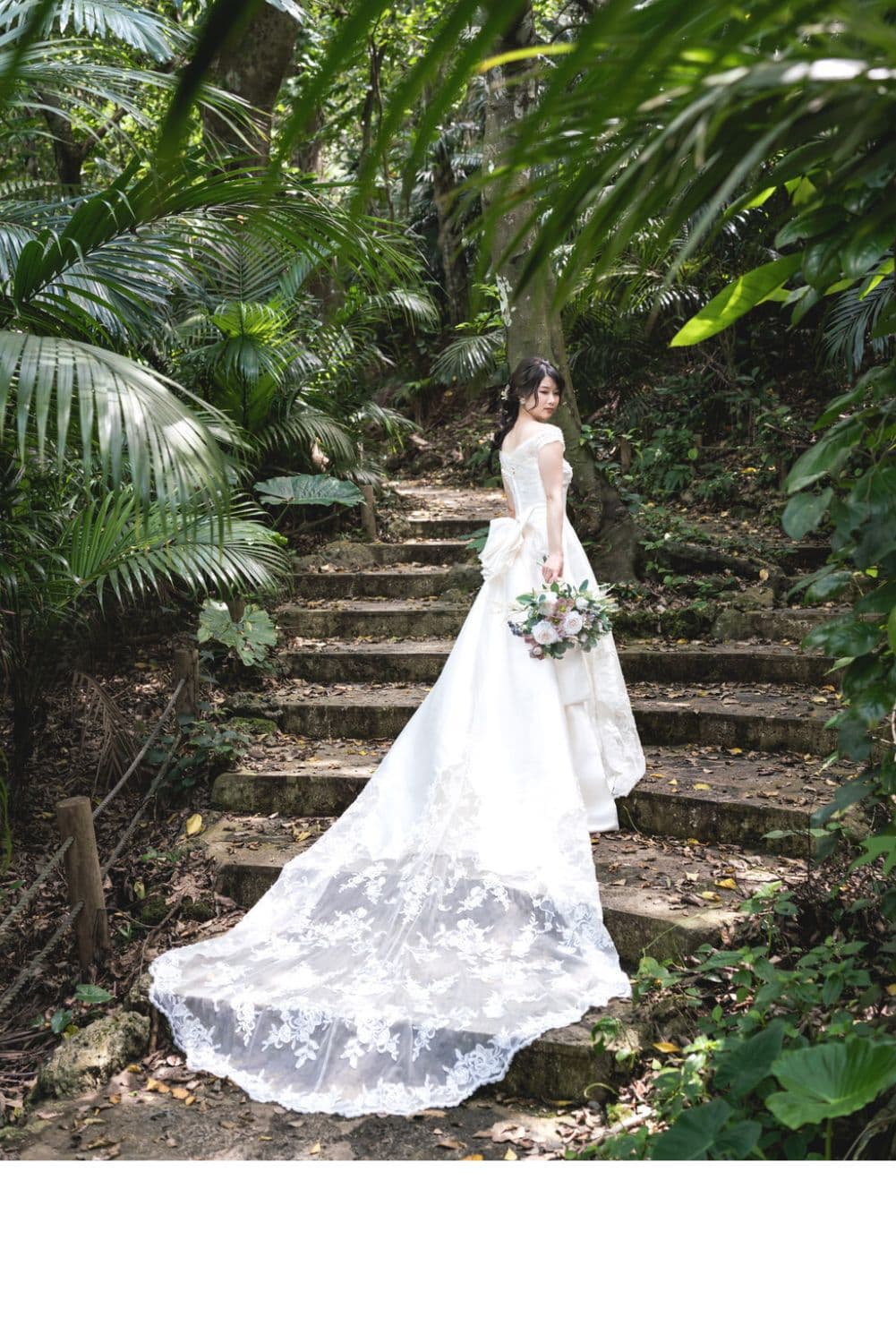 グリーンに囲まれた石階段を上る新婦の後ろ姿