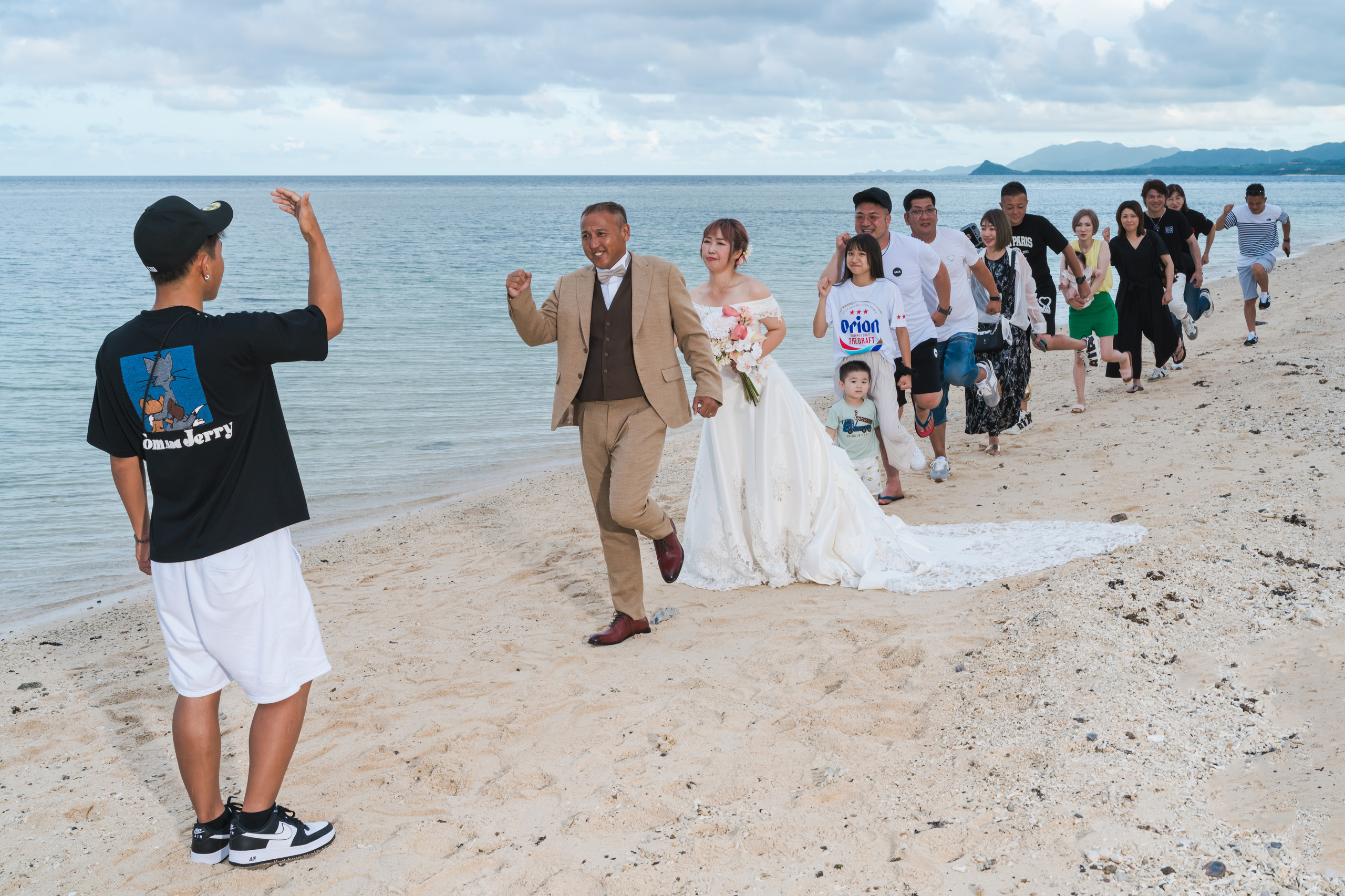 浜辺で行進する新郎新婦と家族