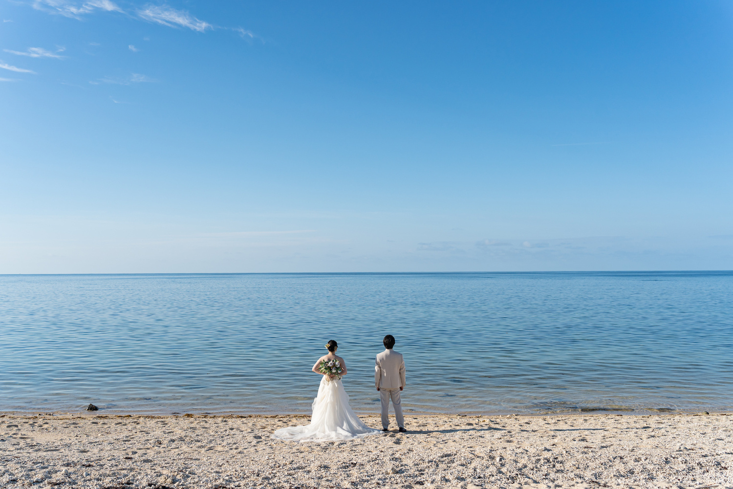 海を眺める新郎新婦の後ろ姿