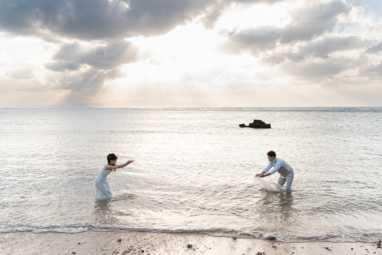 海に入って水をかけ合う新郎新婦