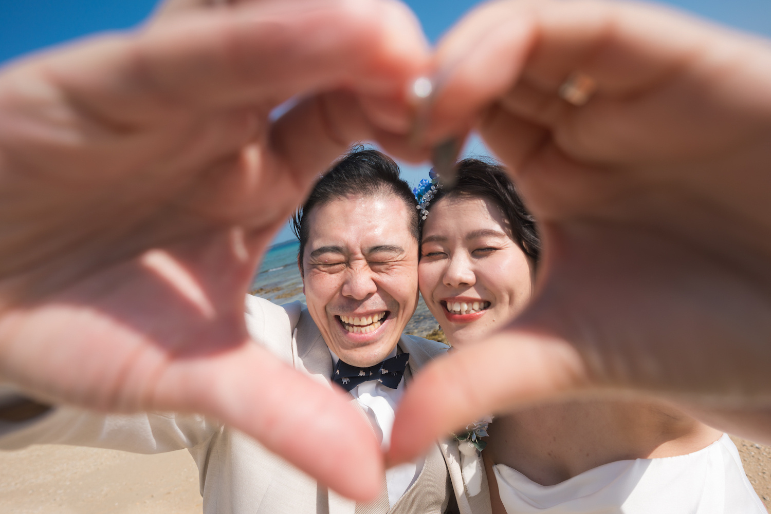 手で作ったハートの中に入って笑う新郎新婦