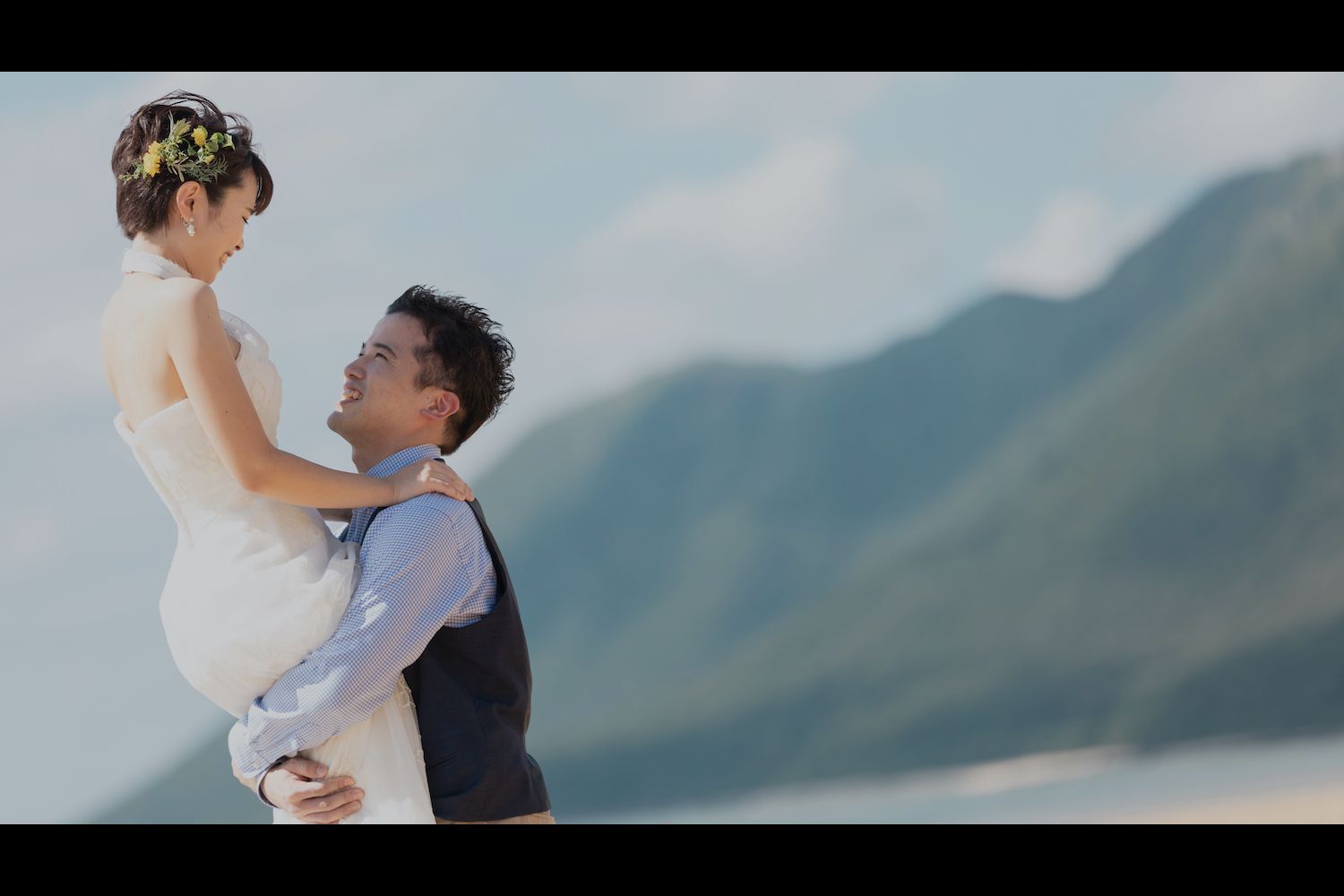 西表島の山々を背景に新婦を抱き上げる新郎