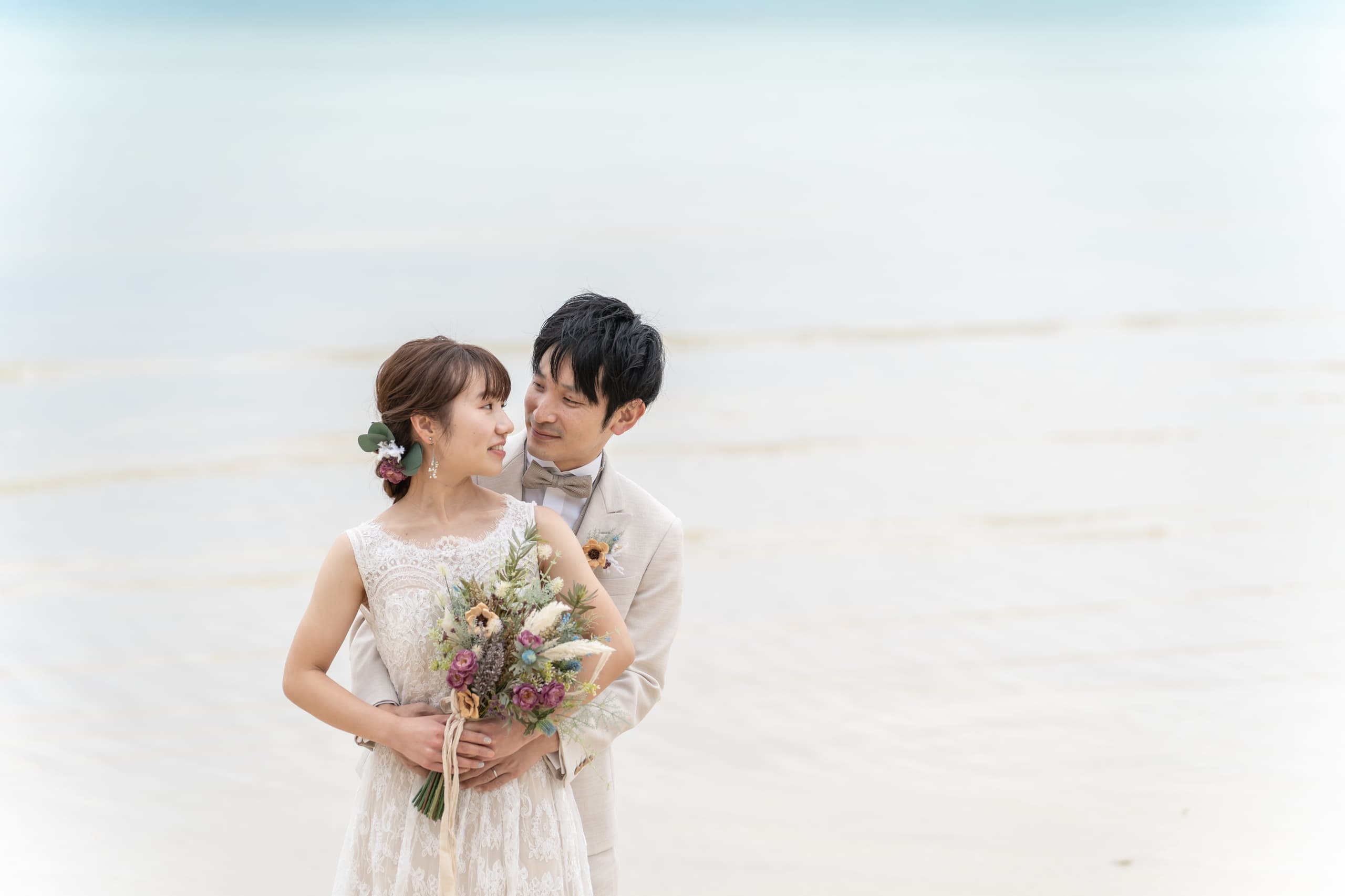 海を背景に抱き合う新郎新婦