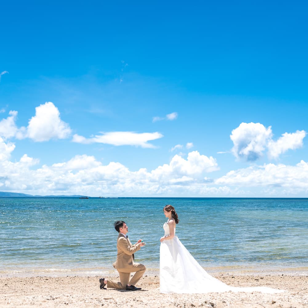 青い海を背景に新婦へプロポーズする新郎