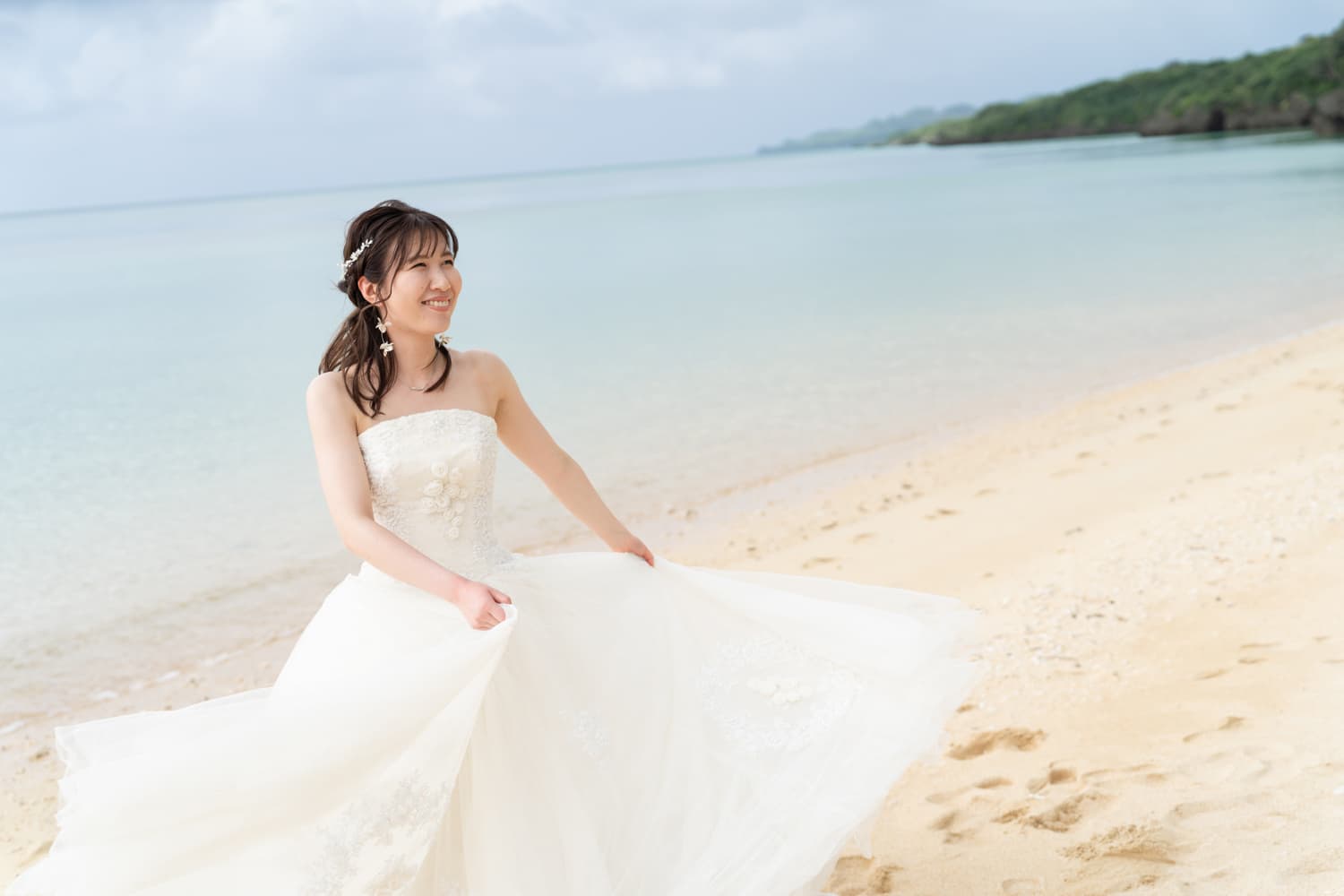 海を背景にドレスを靡かせる新婦