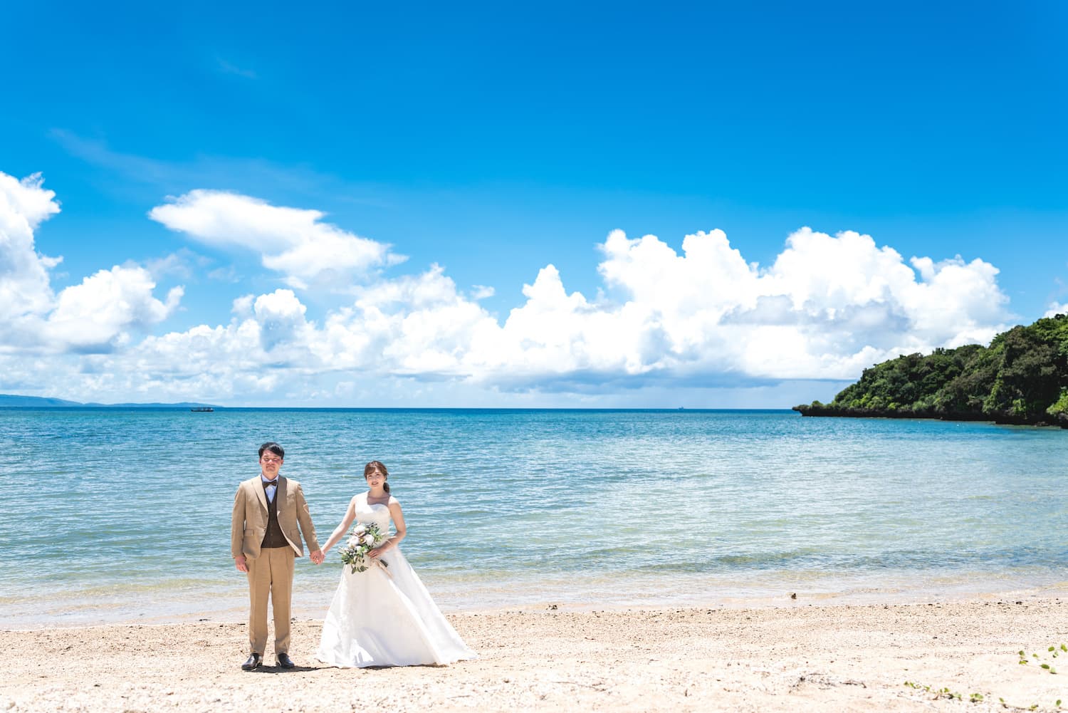 海を背景に手を繋いで立つ新郎新婦