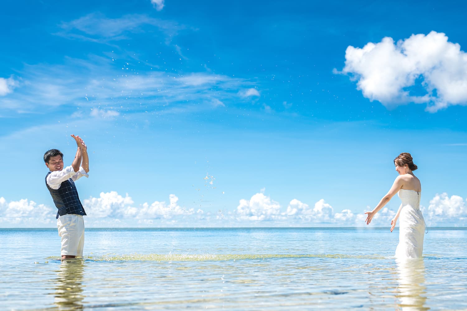 海に入って水をかけあう新郎新婦