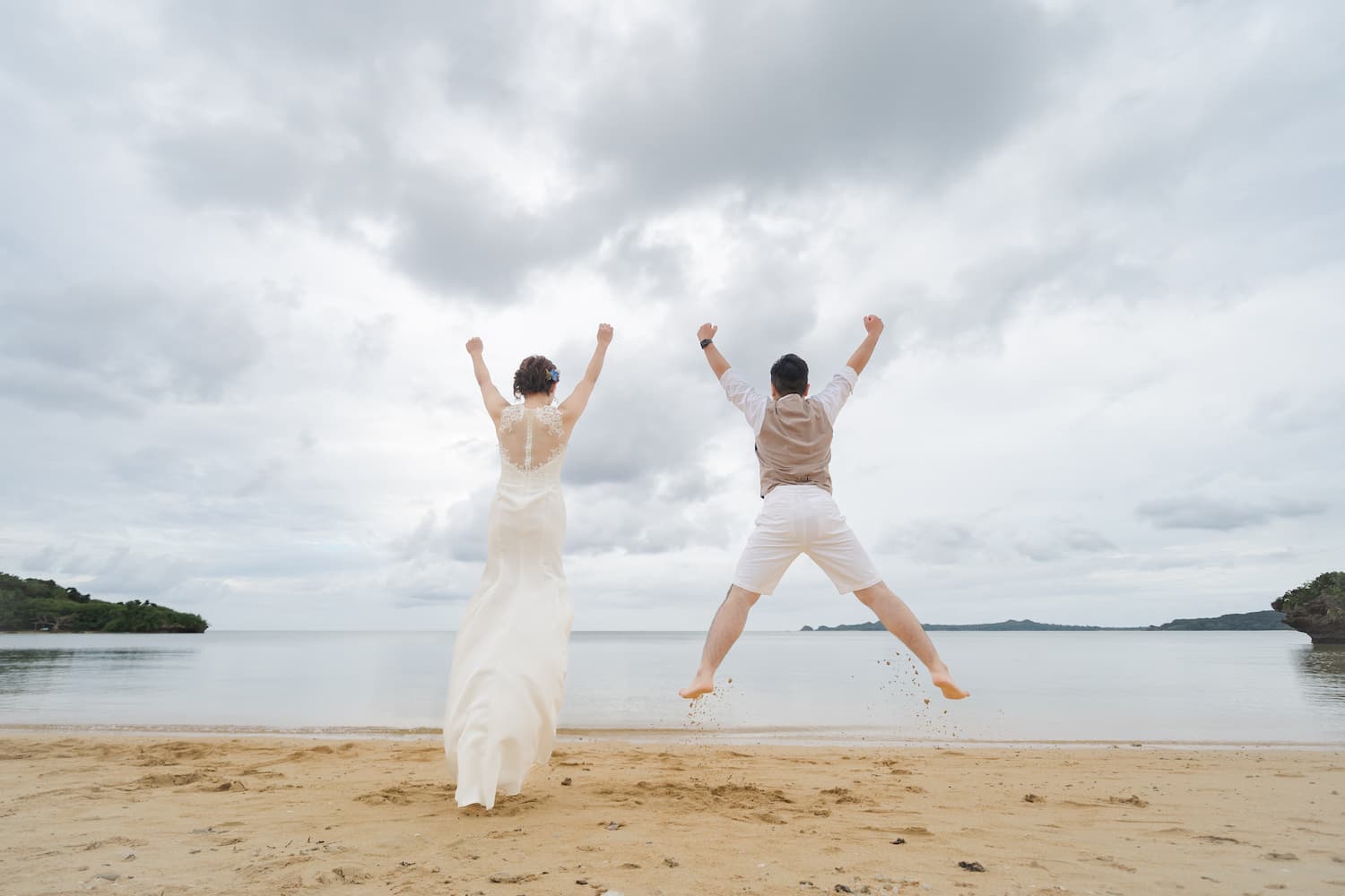 海に向かって大きくジャンプする新郎新婦