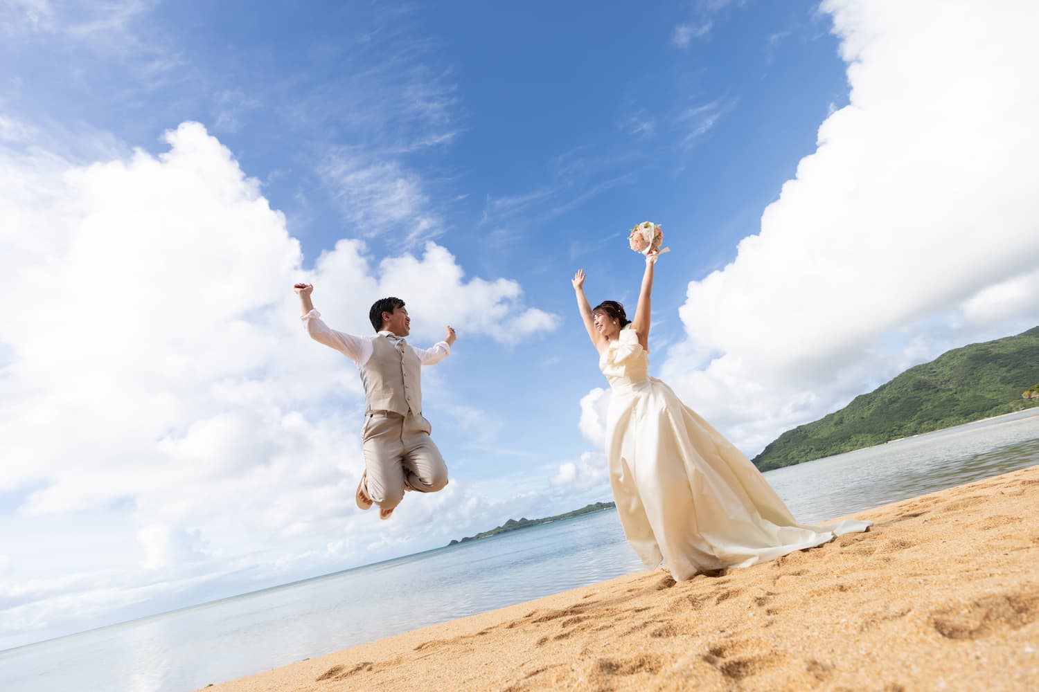 海と空を背景に大きくジャンプする新郎新婦