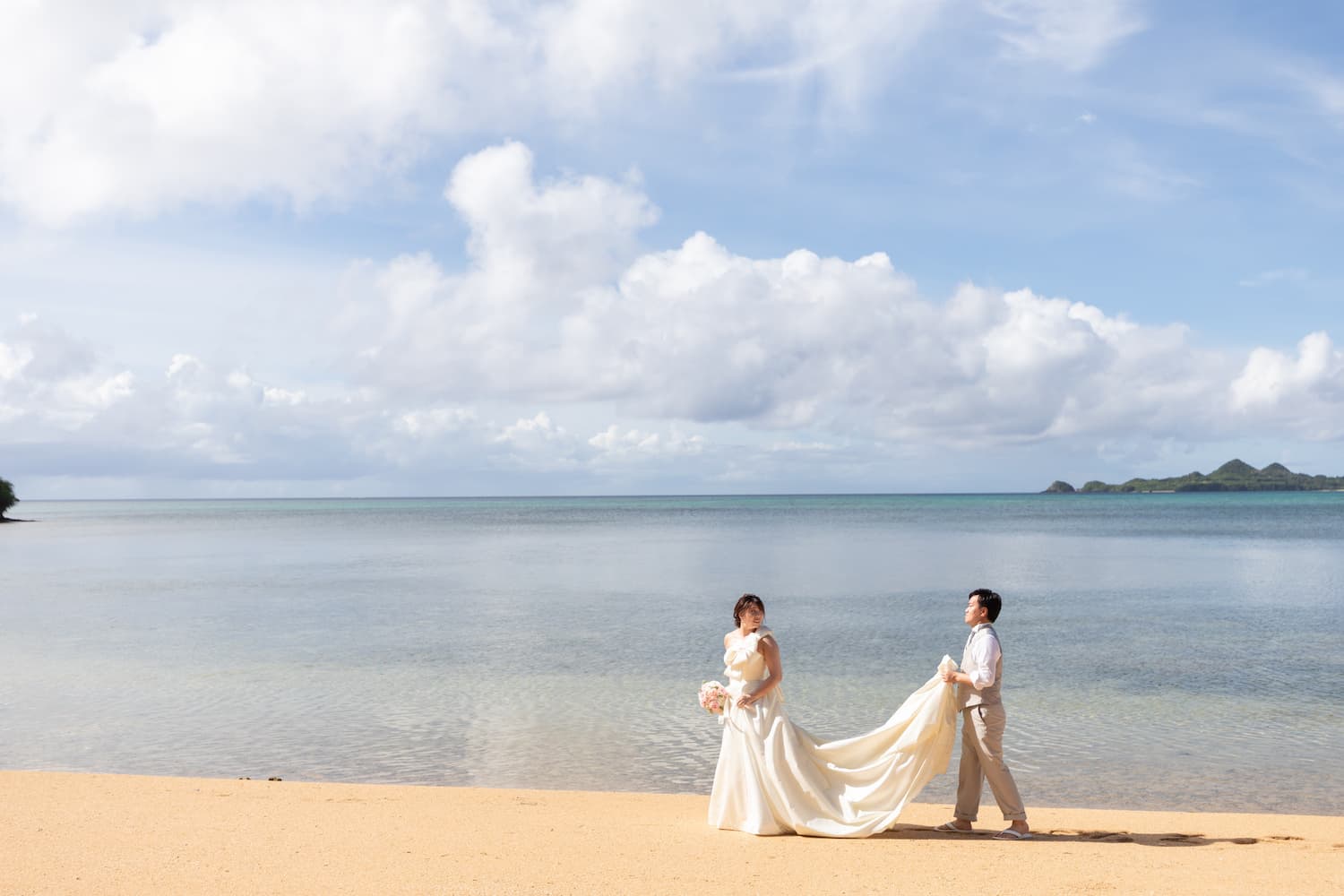 海を背景に歩く新郎新婦