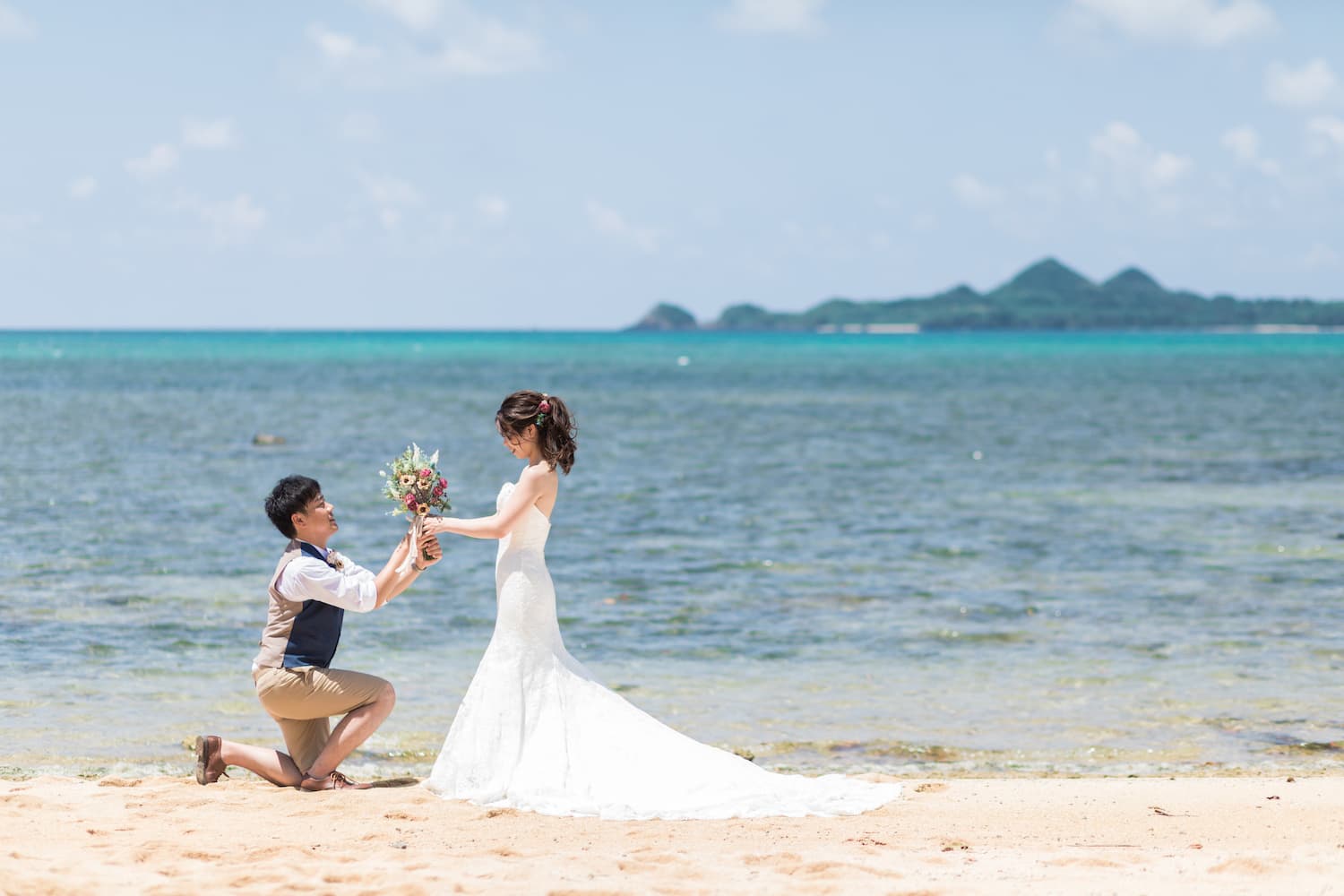 ビーチで海を背景に新婦へブーケを贈る新郎